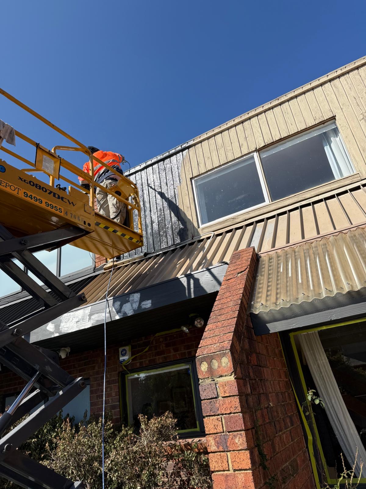 Two-storey residential home exterior painting with scissor lift